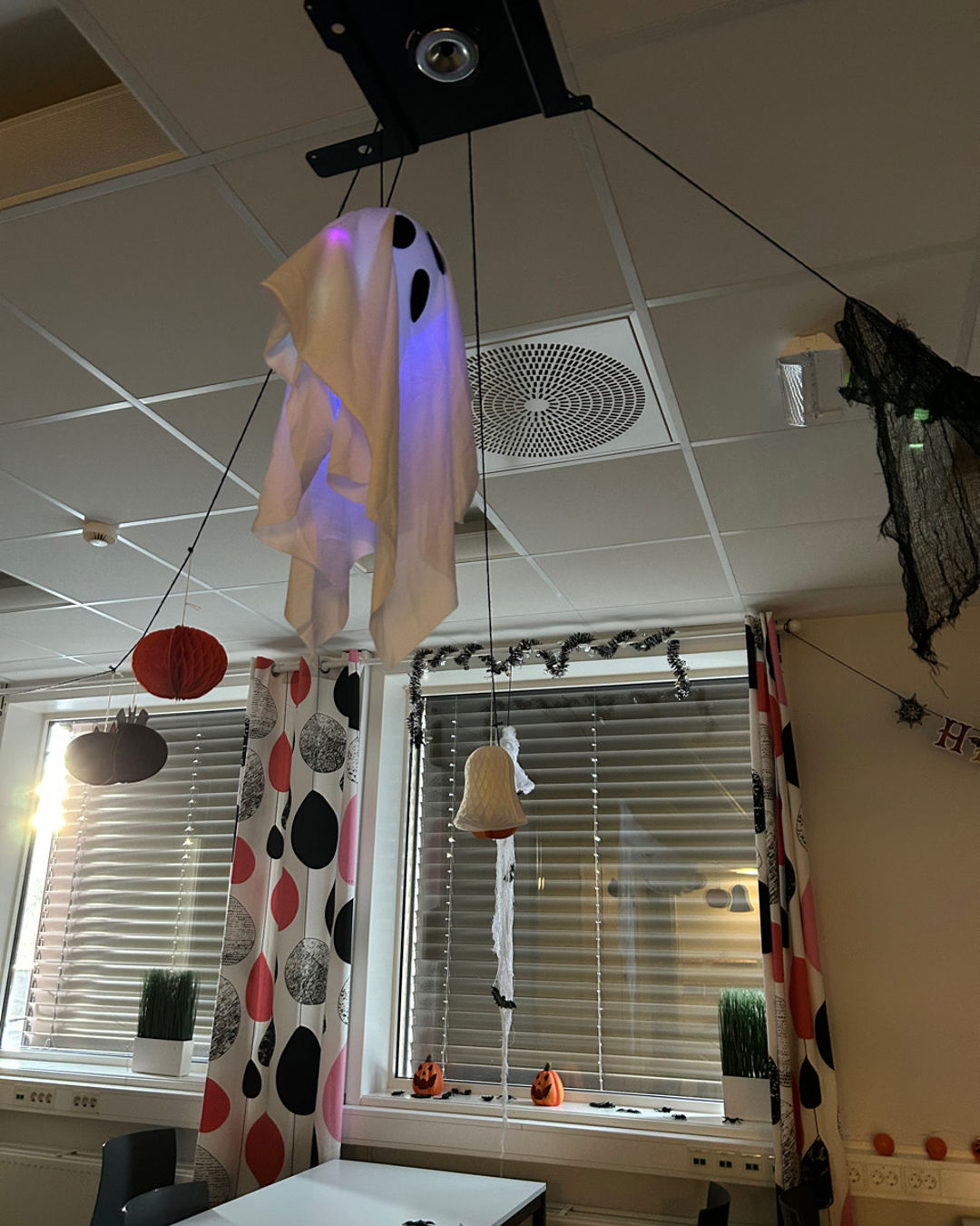 et rom med et bord og en lampe og et vindu med gardin