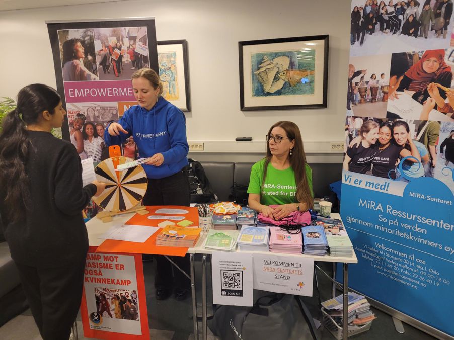 en gruppe mennesker ved et bord med bøker og plakater