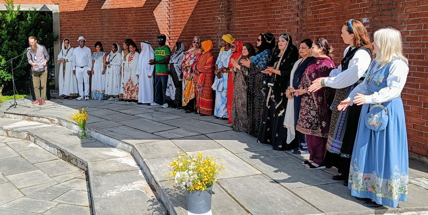 En gruppe mennesker i kapper og kjoler som står utenfor