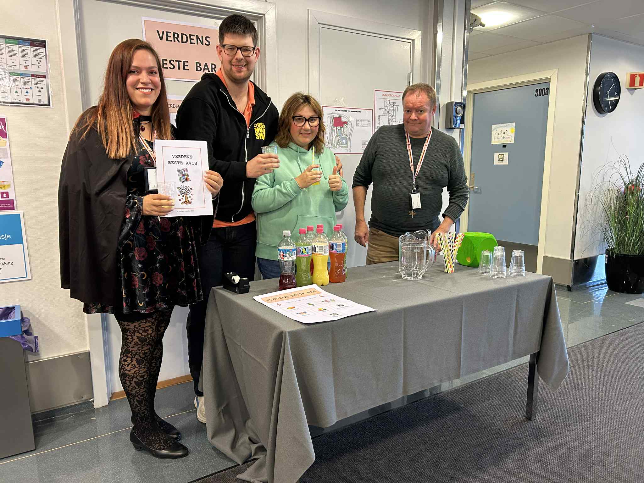 en gruppe mennesker som står rundt et bord med et skilt