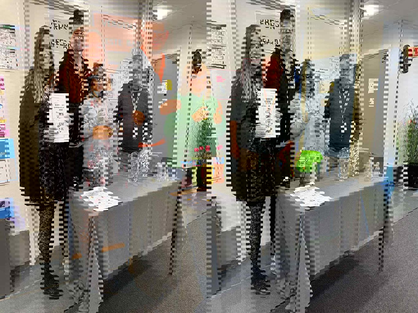 en gruppe mennesker som står rundt et bord med et skilt