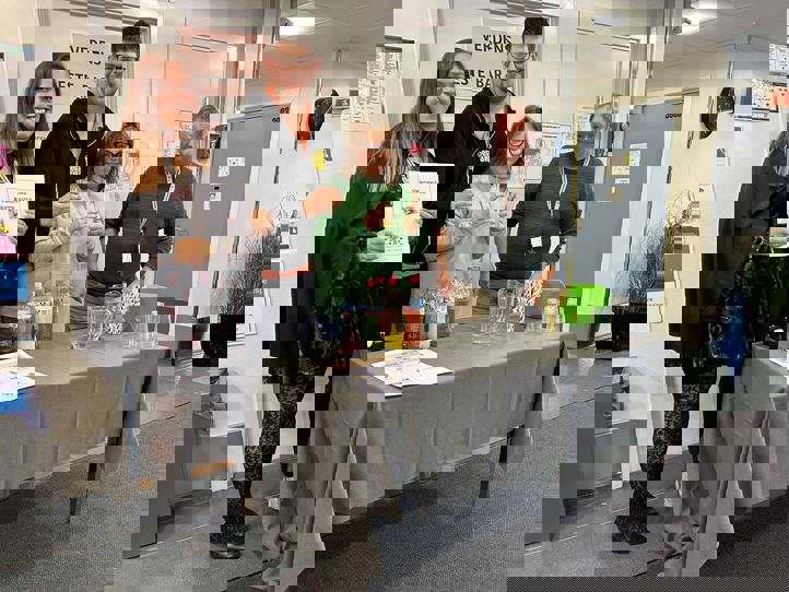 en gruppe mennesker som står rundt et bord med et skilt