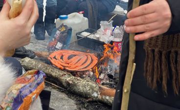 En person som holder en pinne over et bålsted med en pizza på