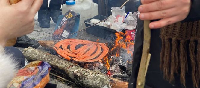 En person som holder en pinne over et bålsted med en pizza på