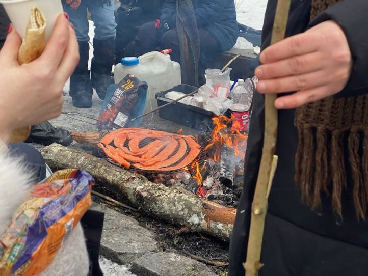 En person som holder en pinne over et bålsted med en pizza på