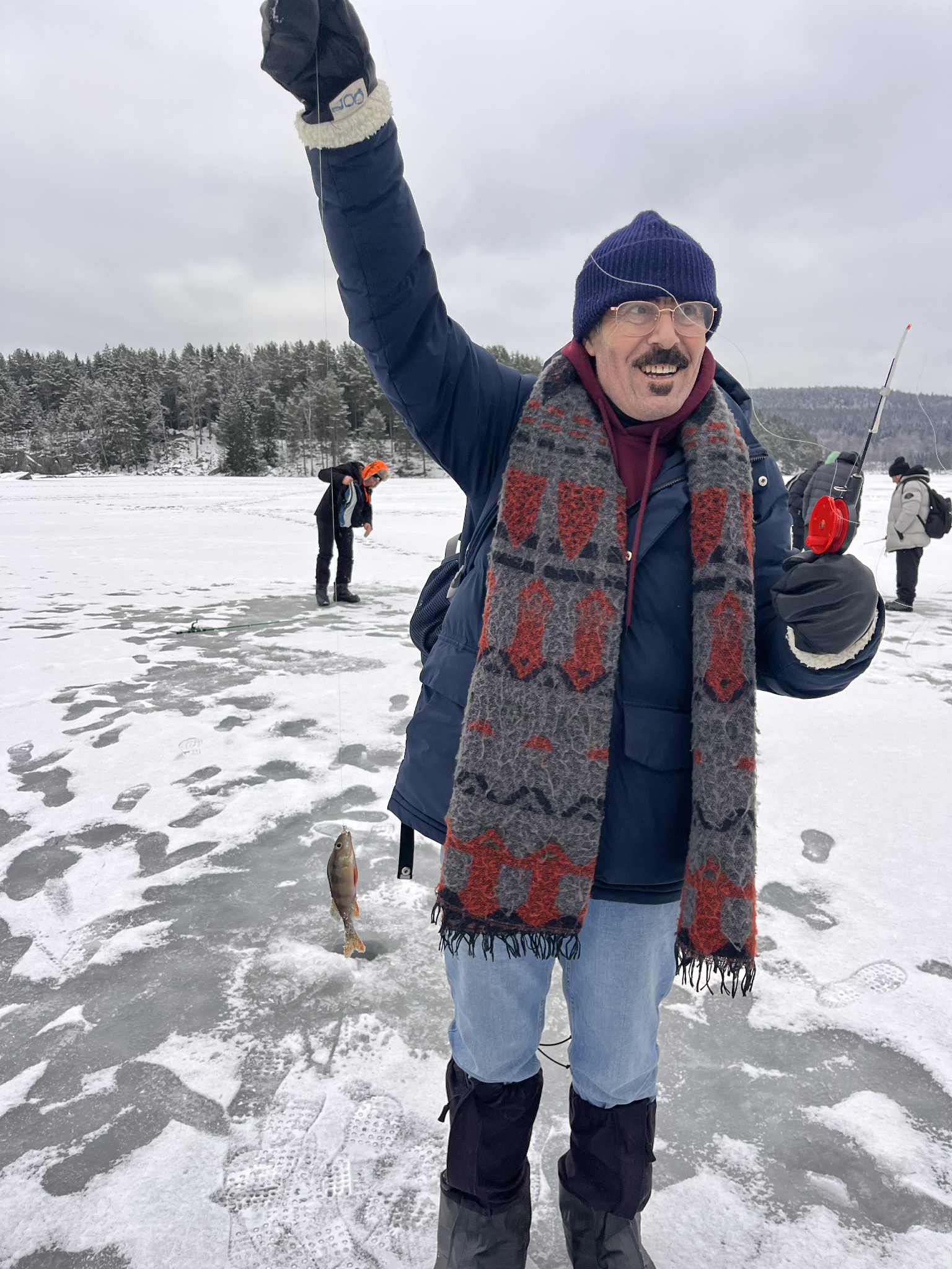 en person i skijakke som holder en pinne i snøen