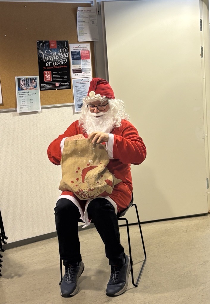 En person i julenissedrakt sitter i en stol med en stor veske